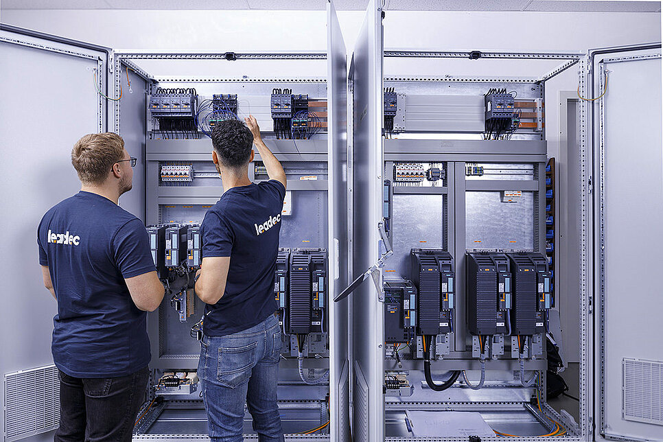 Two Leadec employees checking a switch cabinet.