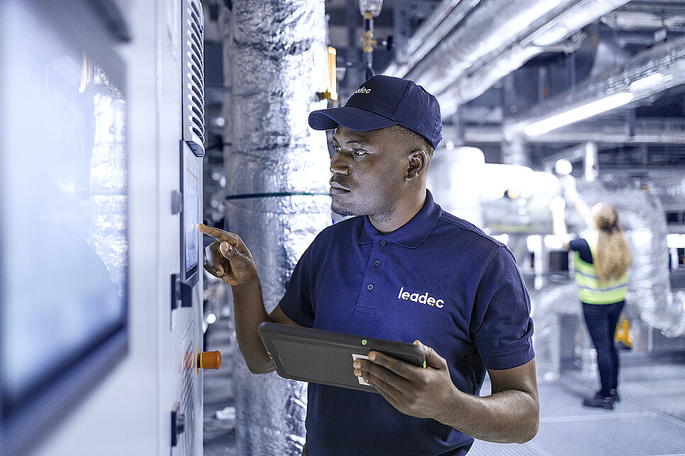 Leadec employee in a factory in front of screen.