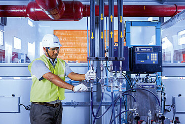 A Leadec employee checking the pipes at a supply system  in a production facility.