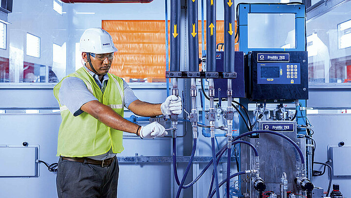 A Leadec employee checking the pipes at a supply system  in a production facility.
