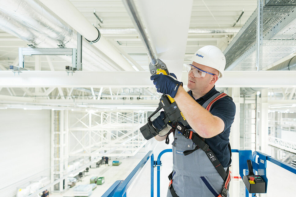 Leadec employee installing media supply on the ceiling of a factory.