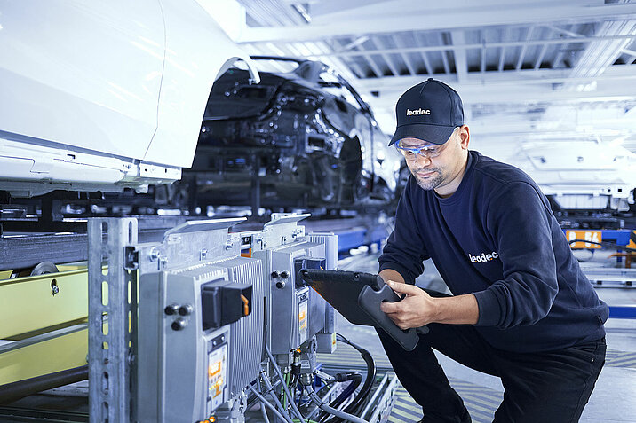 A Leadec employee configures an inverter at a conveyor belt.