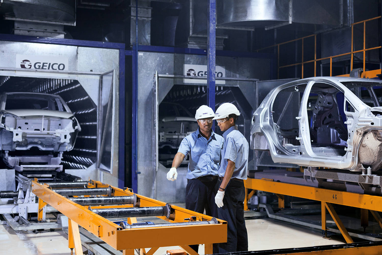 Two Leadec employees at a conveyor belt in an automotive factory.
